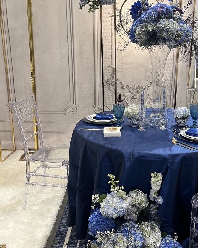 Navy blue reception tablescape with elevated blue hydrangea centerpiece and ghost chairs