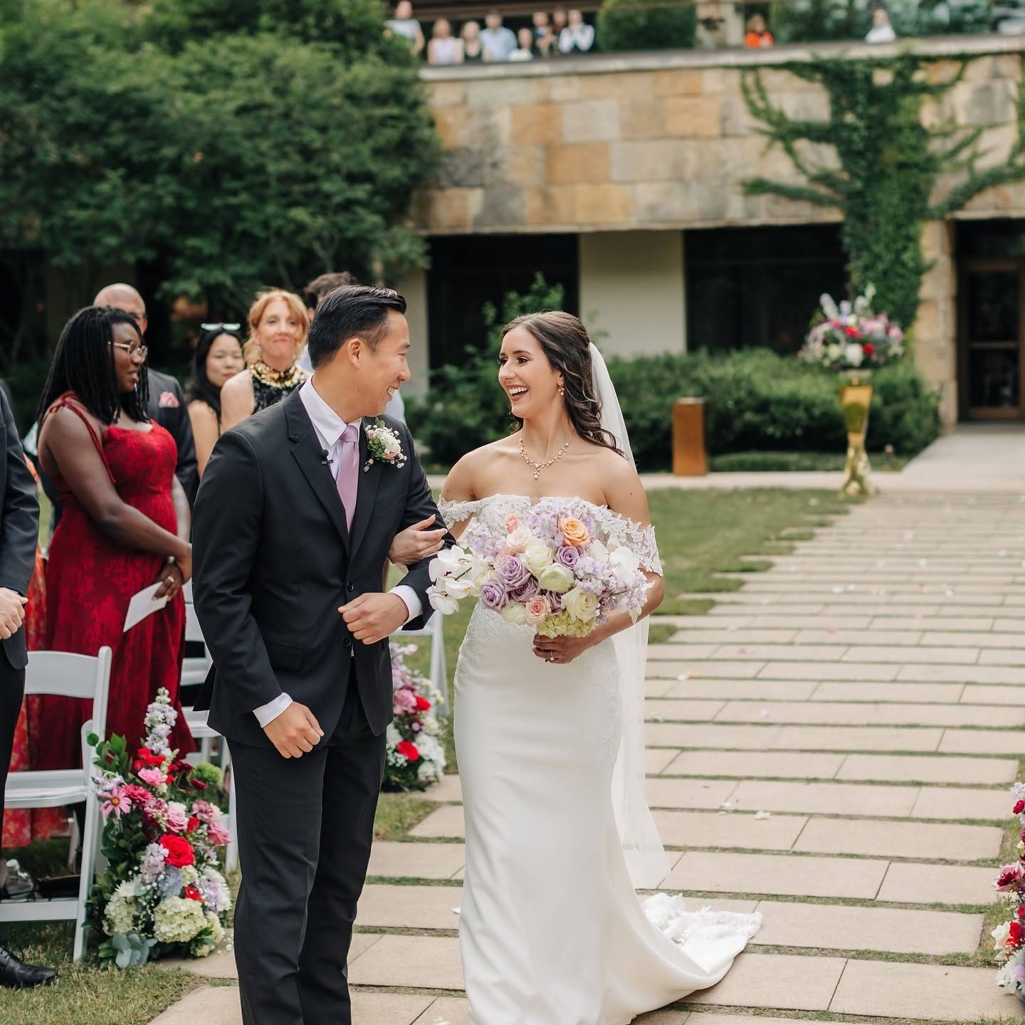 Bride and groom walking the aisle with a pastel bouquet and aisle florals
