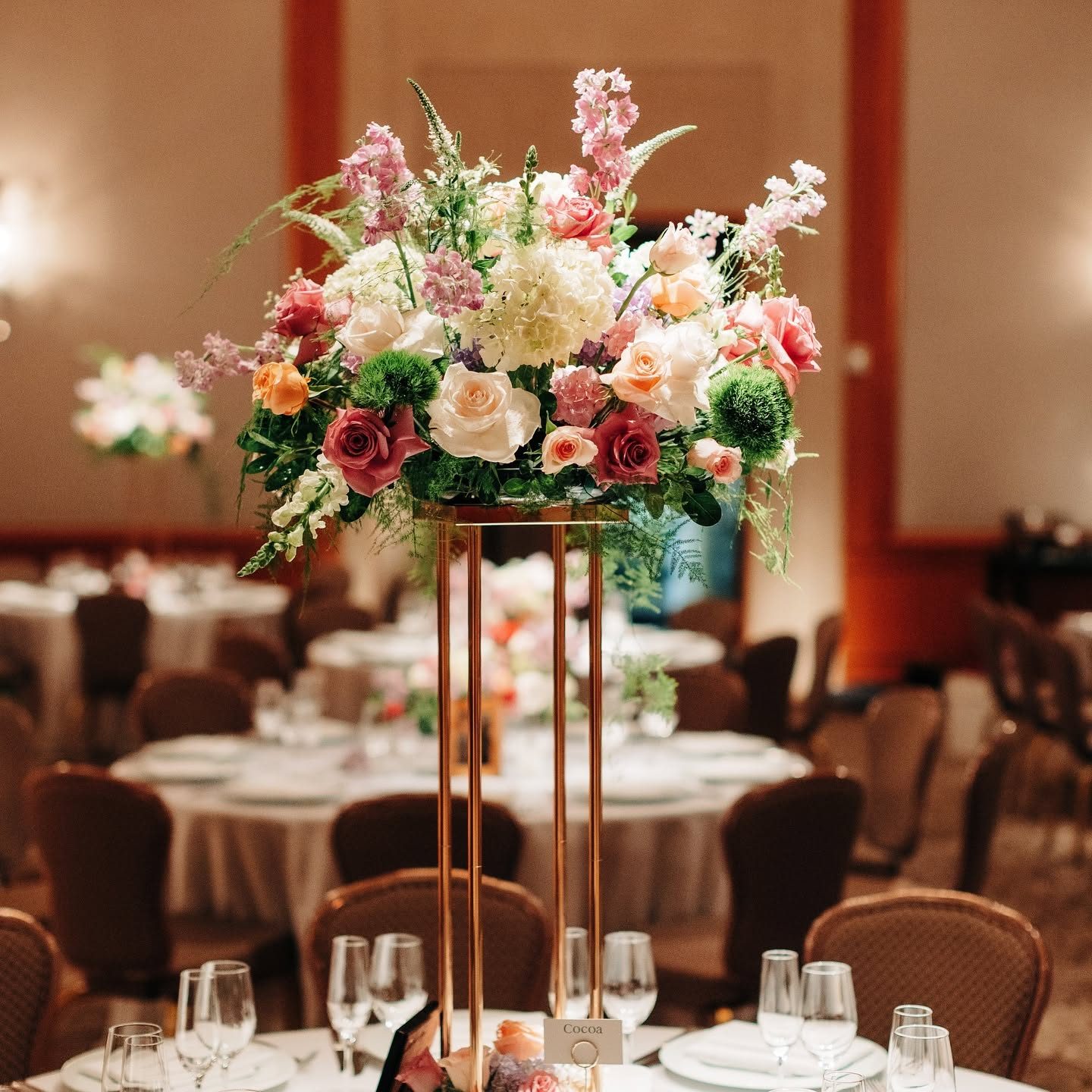 Tall gold-stand reception centerpiece of garden roses, hydrangea, stock, and veronica