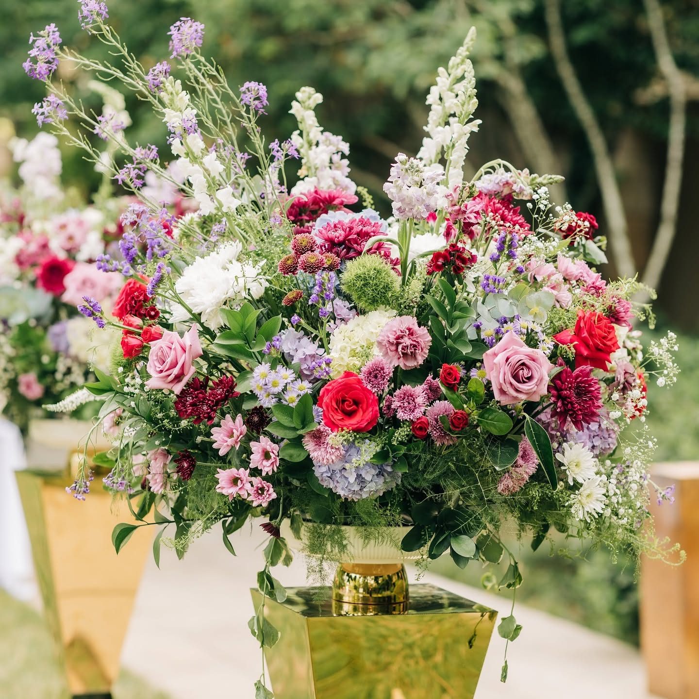 Garden-style ceremony urn overflowing with roses, mums, stock, and statice