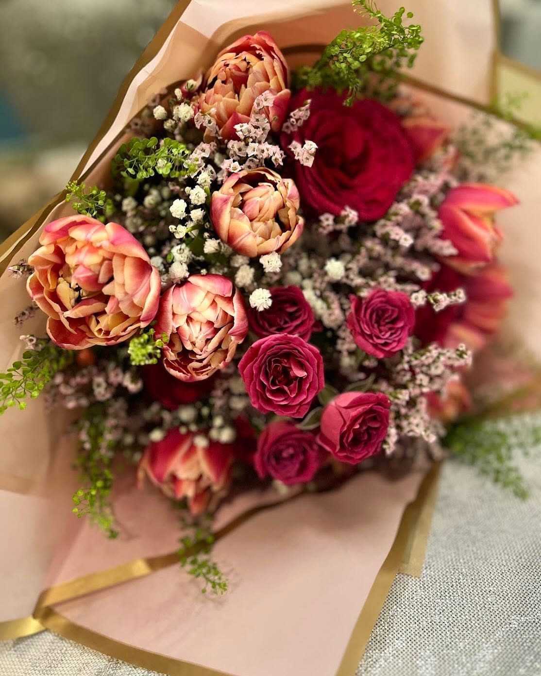 Hand-tied wrapped bouquet of peony tulips, garden roses, and waxflower